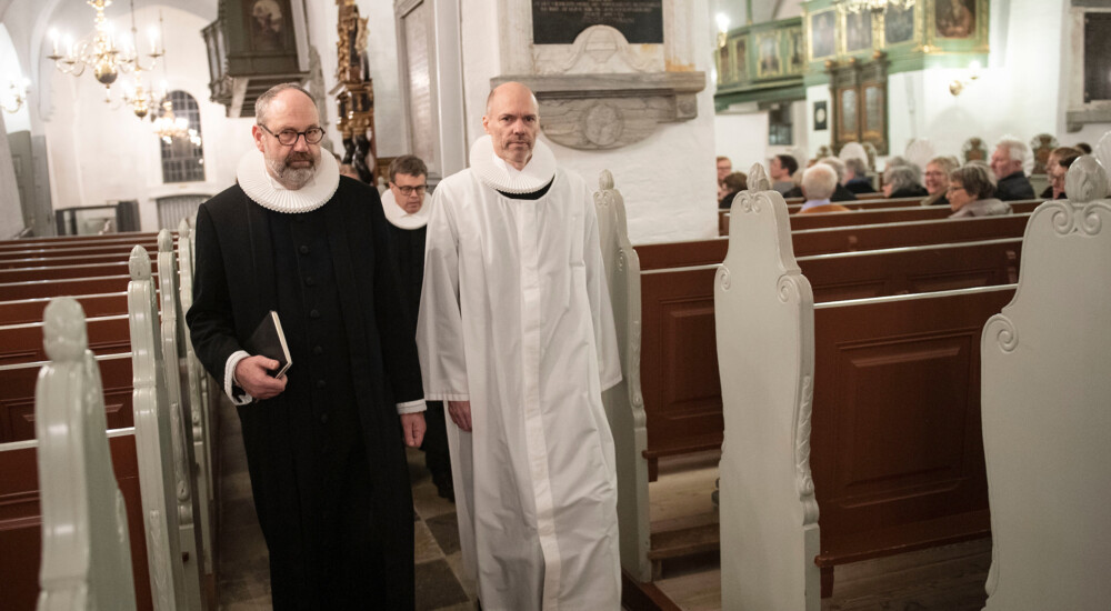 Cand. theol. Jack Nørdam Pedersen og domprovst Jakob Køhn Andersen går mellem kirkebænke