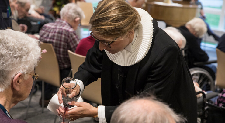 Præst hælder nadvervin op i glas