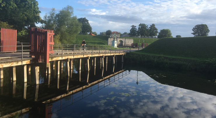 Cyklist på bro over vandgrav ved kastellet