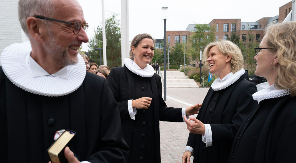 Præster griner og hilser på hinanden udenfor kirke